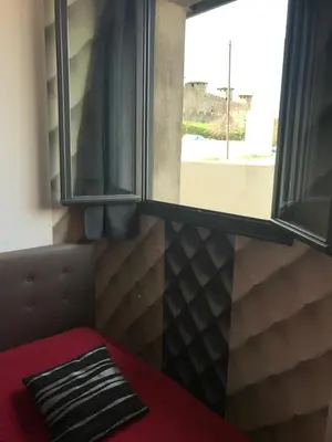a room with two windows and a red bed in front of a window at La Rapière in Carcassonne