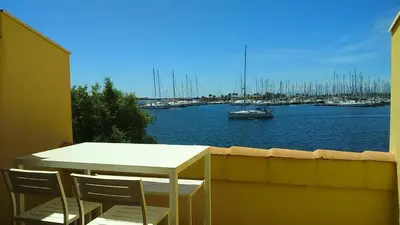a table and chairs on a balcony overlooking a marina at EN BORD DE MER in Gruissan
