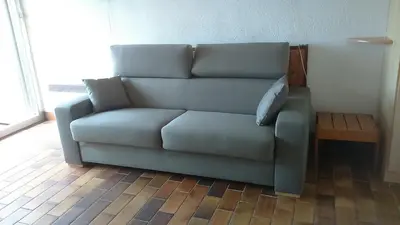 a blue couch in a living room with a table at EN BORD DE MER in Gruissan