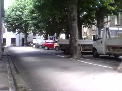 a street with cars parked on the side of the road at La maison des vendangeurs in Trausse