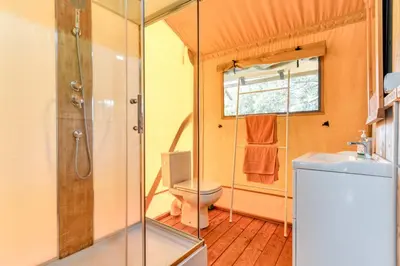 a bathroom with a shower and a toilet and a sink at Glamping Tent Joy in Vélieux