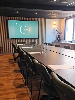 a conference room with tables and chairs and a screen at Hôtel Le C - Boutique Hôtel in Narbonne