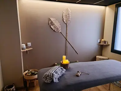 a bedroom with a blue bed with a feather lamp on the wall at Hôtel Le C - Boutique Hôtel in Narbonne
