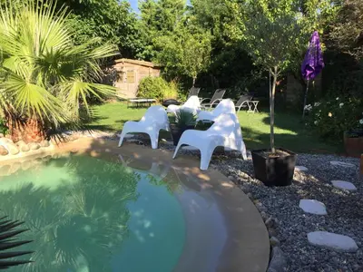 a group of white chairs sitting next to a pool at Domaine Le Village in Villenouvelle