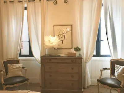 a bedroom with a dresser and two chairs and windows at Domaine Le Village in Villenouvelle