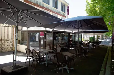 an outdoor restaurant with tables and chairs with umbrellas at Maison du Cassoulet in Castelnaudary