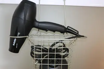 a hair dryer in a basket hanging from a wall at Studio au Coeur du Village avec terrasse et parking proche de Pamiers in Verniolle