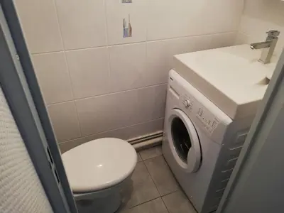 a bathroom with a toilet and a sink and a washing machine at Maison près de la plage in Port-la-Nouvelle