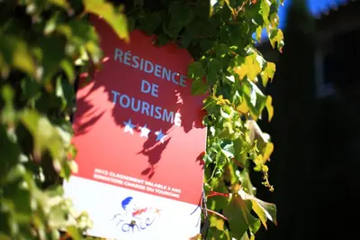 a red sign hanging from a tree with leaves at FranceComfort - L'Espinet in Quillan