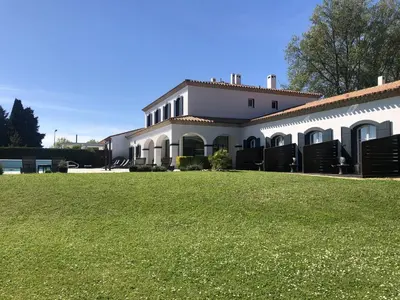 a large white building with a large grass yard at Hôtel La Bastide Saint Martin in Carcassonne