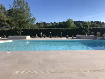 a swimming pool with blue water in a yard at Hôtel La Bastide Saint Martin in Carcassonne
