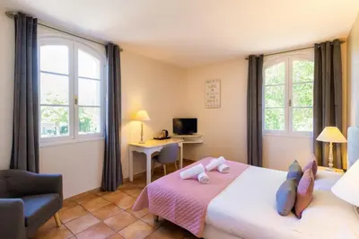 a bedroom with a bed with a chair and a desk at Hôtel La Bastide Saint Martin in Carcassonne