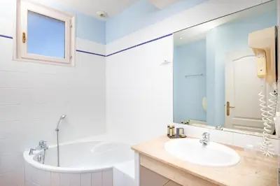 a white bathroom with a tub and a sink at Hôtel La Bastide Saint Martin in Carcassonne