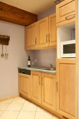 a kitchen with wooden cabinets and a white microwave at Jardin de Palme in Lapalme