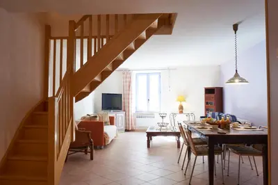 a living room with a dining room table and a staircase at Jardin de Palme in Lapalme
