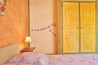 a bedroom with a bed with purple flowers on the wall at Jardin de Palme in Lapalme