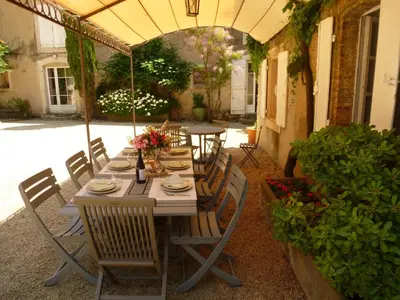 a table and chairs under an umbrella on a patio at Château La Villatade in Sallèles-Cabardès