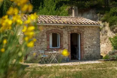a small stone house with a table and chairs outside at Château La Villatade in Sallèles-Cabardès