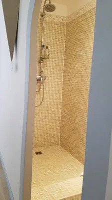 a bathroom with a shower with yellow tile at Château La Villatade in Sallèles-Cabardès