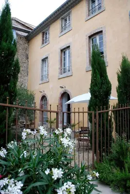 a fence in front of a house with white flowers at La Maison Vieille Maison d'Hôtes & Gîtes in Carcassonne