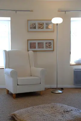 a living room with a white chair and a lamp at La Maison Vieille Maison d'Hôtes & Gîtes in Carcassonne