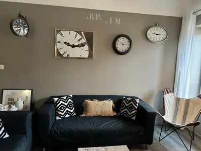 a living room with a black couch and clocks on the wall at La Maison Vieille Maison d'Hôtes & Gîtes in Carcassonne