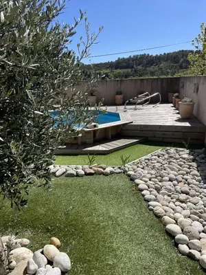 a backyard with a swimming pool and a rock garden at Le Gîte de la Bade in Villegailhenc