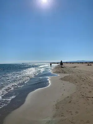 a beach with people walking on the sand and the ocean at Studio Les Régates avec loggia et parking gratuit Plage du Grazel Gruissan in Gruissan