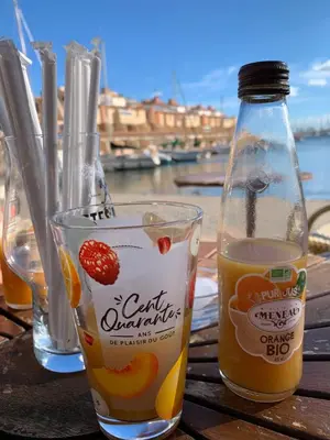 a bottle of orange juice and a glass on a table at Studio Les Régates avec loggia et parking gratuit Plage du Grazel Gruissan in Gruissan