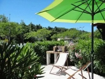 a green umbrella and two chairs and a table at Villa T2 Mezzanine 4 pers avec Parking à La Franqui - FR-1-81-370 in La Franqui-Plage