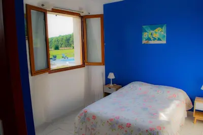 a blue bedroom with a bed and a window at Gîte Lempery in Puéchoursi