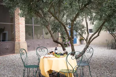 a table with chairs and a bottle of wine on it at Château Canet in Rustiques