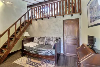 a living room with a couch under a staircase at Domaine de Hurlevent in Montgaillard-Lauragais