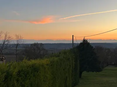 a sunset over a hedge with a tree on a hill at Domaine de Hurlevent in Montgaillard-Lauragais