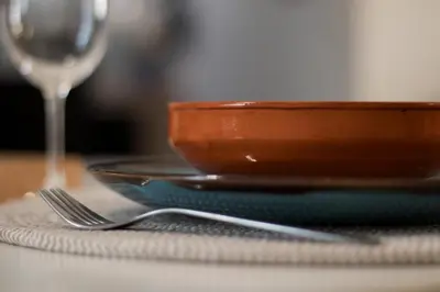 a bowl and a plate on a table with a wine glass at Le Temps d'Eugène Centre historique in Narbonne