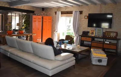 a woman sitting on a couch in a living room at Les Treillettes in Puylaurens