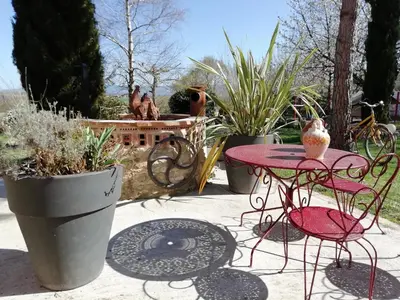 a patio with a table and chairs and potted plants at Les Treillettes in Puylaurens