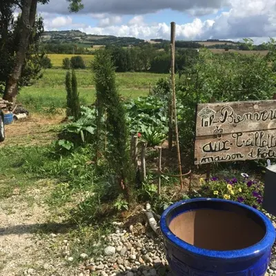 a garden with a blue barrel and a sign at Les Treillettes in Puylaurens