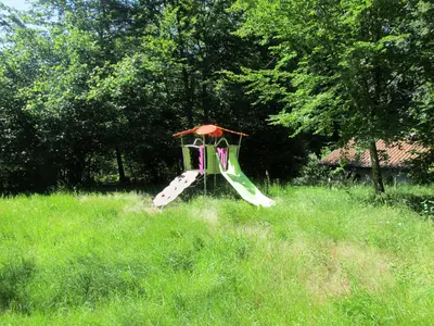a slide in the middle of a grassy field at La Truite in Saint-Amans-Valtoret