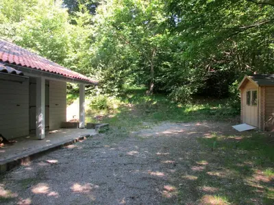 a yard next to a house with a porch at La Truite in Saint-Amans-Valtoret
