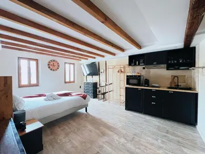 a bedroom with a large bed and a kitchen at Domus Via Domitia in Narbonne
