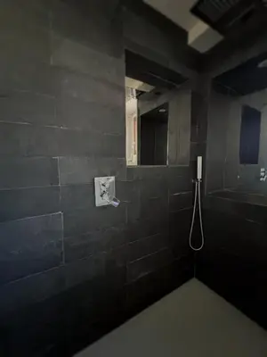 a black bathroom with a shower with a mirror at Domus Via Domitia in Narbonne