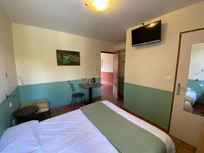 a bedroom with a bed and a desk and a television at Auberge la Table du Curé in Cucugnan