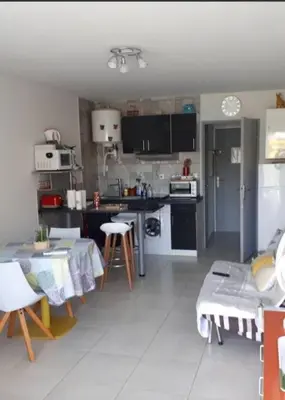 a kitchen with a table and a kitchen with a table and chairs at Studio avec jardinet clim parking in Gruissan