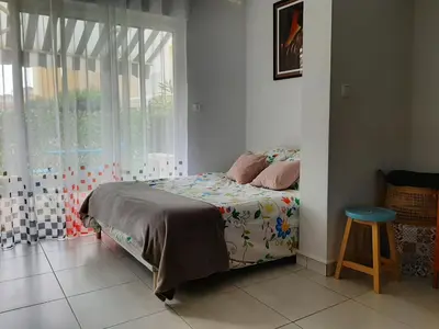 a bedroom with a bed and a window and a stool at Studio avec jardinet clim parking in Gruissan