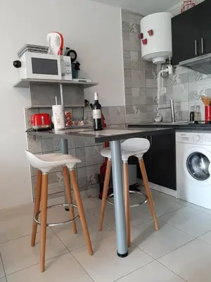 a kitchen with a counter with stools and a microwave at Studio avec jardinet clim parking in Gruissan