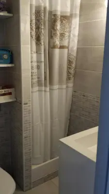 a bathroom with a shower with a white shower curtain at Studio avec jardinet clim parking in Gruissan