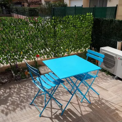 a blue table and two chairs next to a fence at Studio avec jardinet clim parking in Gruissan