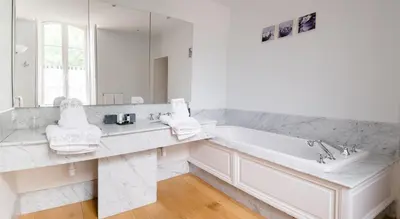a white bathroom with a tub and a large mirror at Château Haut Gléon in Villesèque-des-Corbières