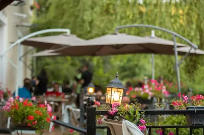 a light on a fence with flowers and an umbrella at Logis hôtel restaurant Auberge de l'Espinouse in Fraisse-sur-Agout